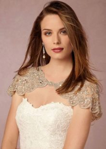 White wedding dress case in combination with a beige lace cape on the shoulders